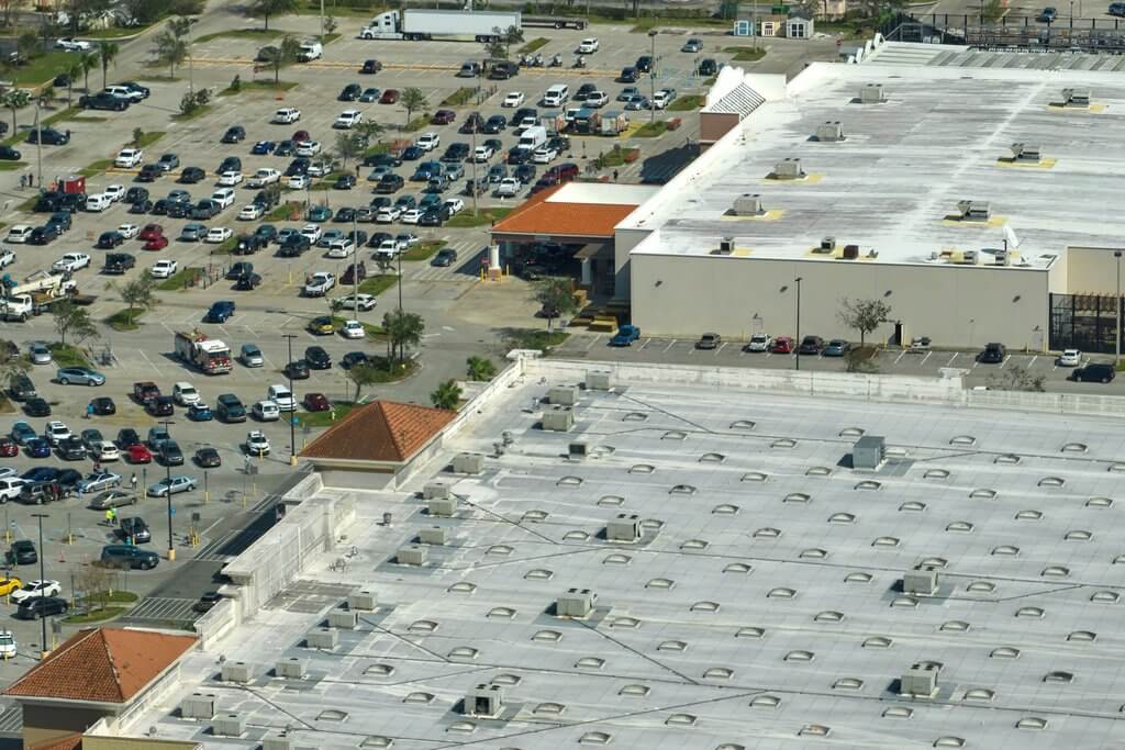 Aerial view of the top of two commercial buildings and a large parking lot 