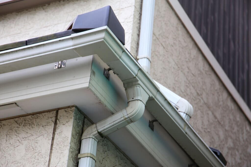 a mint green gutter on the side of a home | gutters and downspout systems