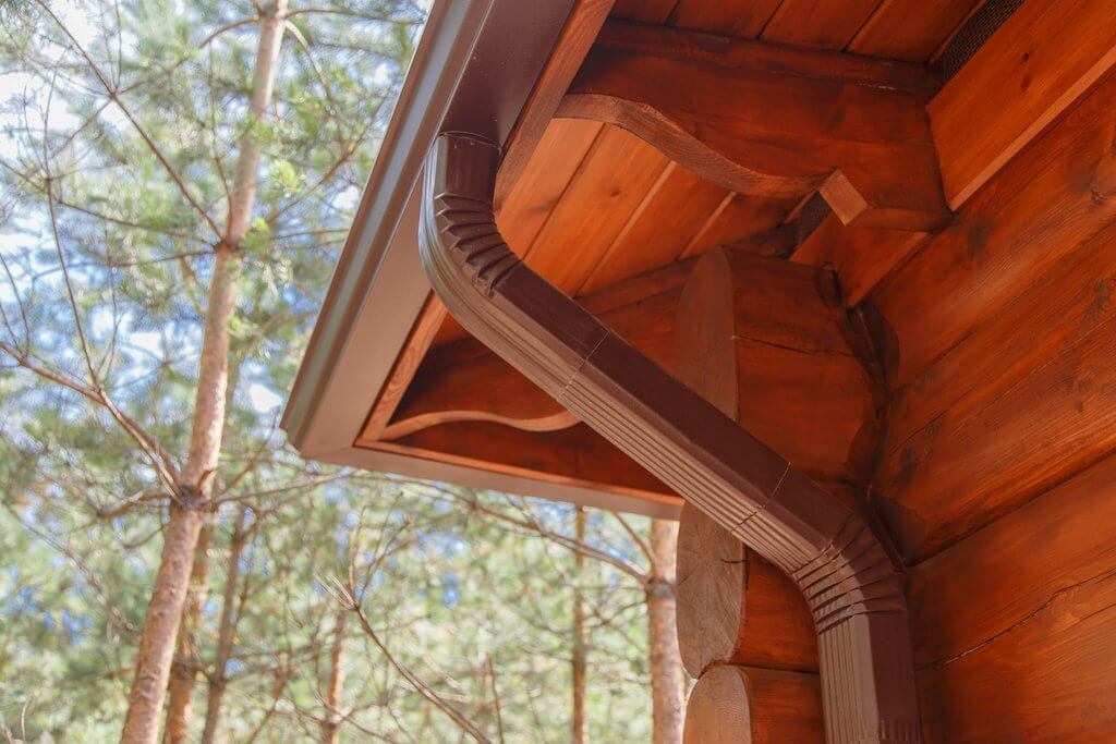 A brown gutter on the side of a wood home 